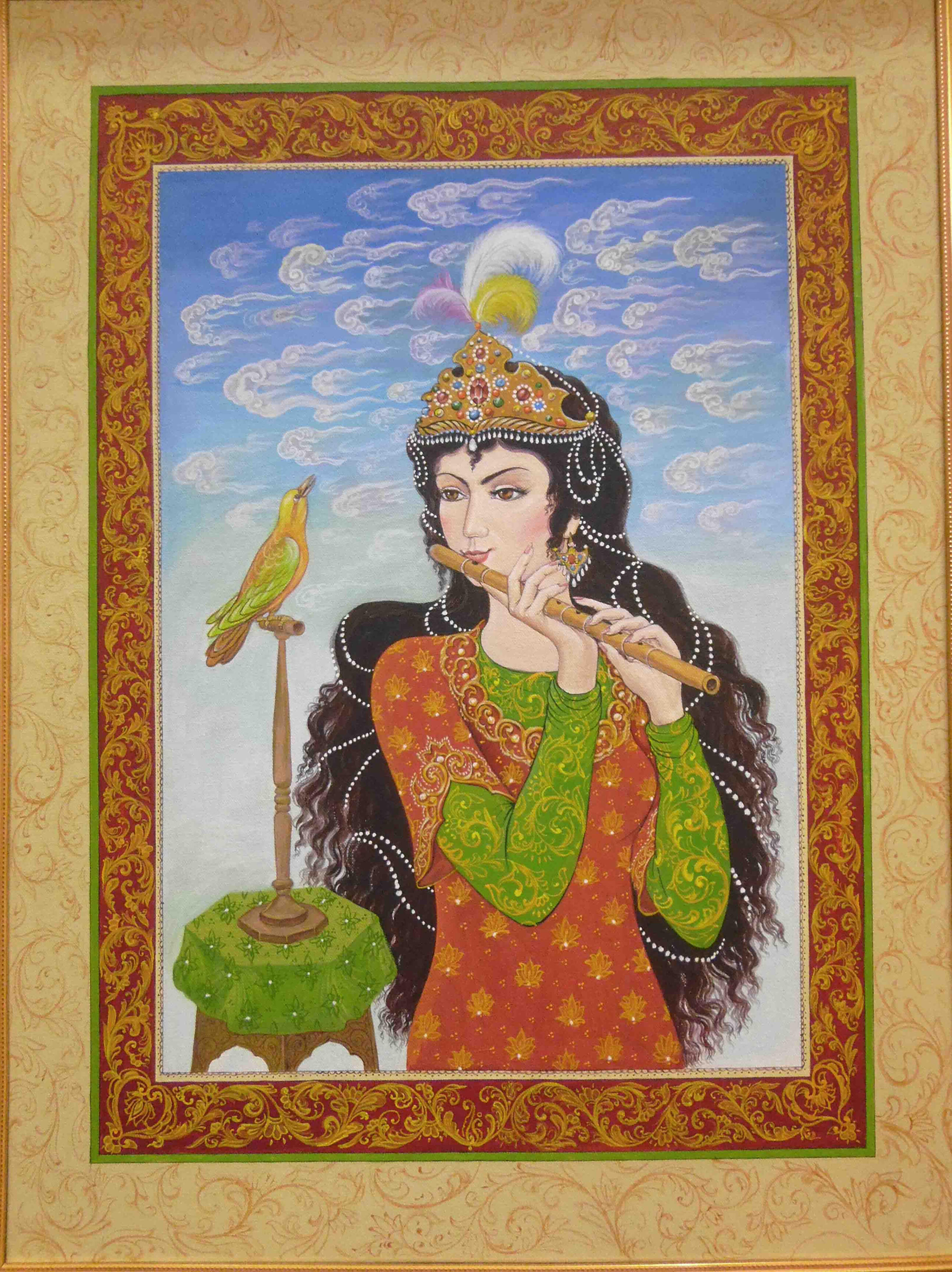 Photo of Olim Kamolzoda sitting at the desk in his workshop. He is the Honoured Artist of the Republic of Tajikistan, a Member of the Union of Artists of the Republic of Tajikistan, and a Specialist of the Miniature Art. Studying the specifics of the work