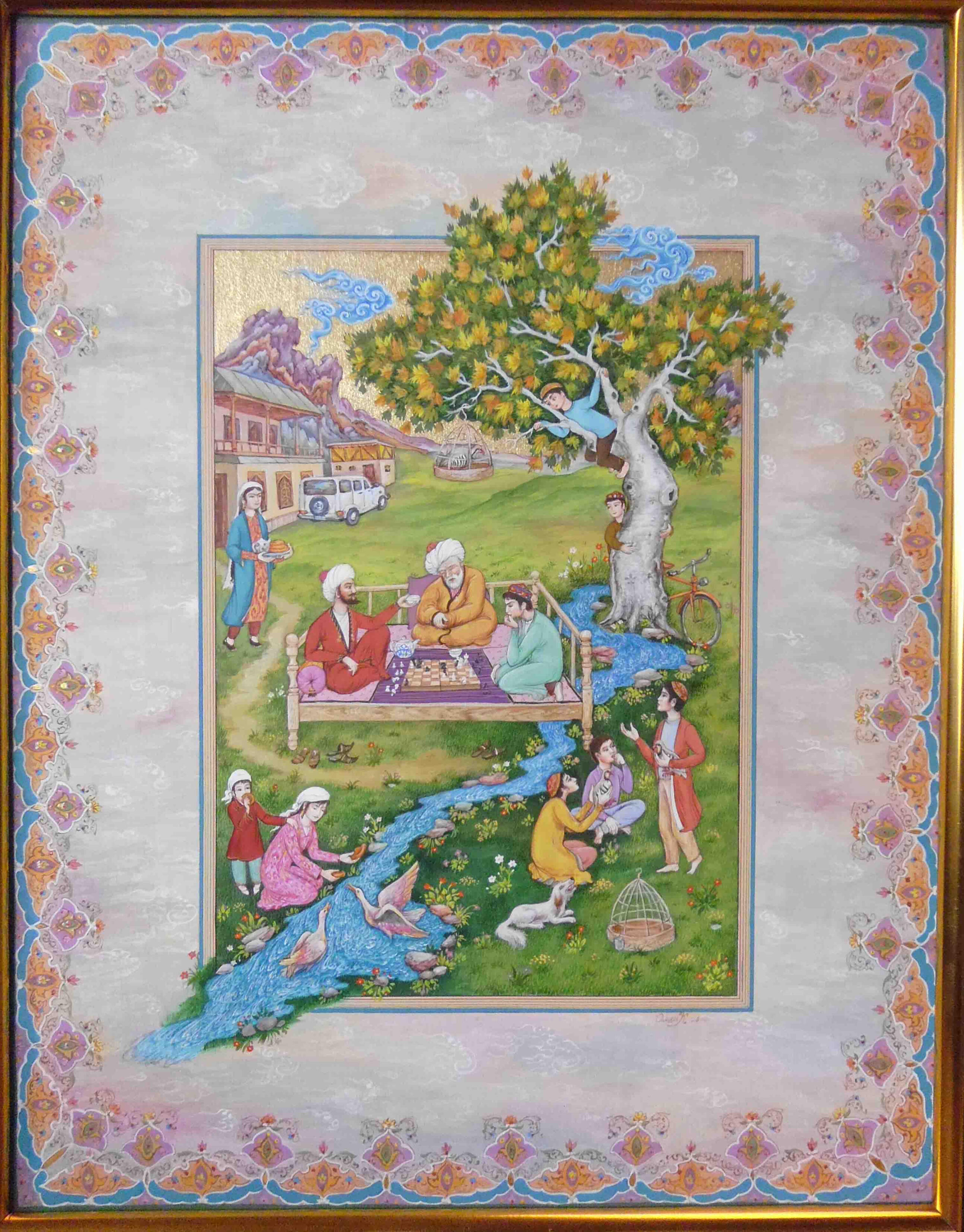 Photo of Olim Kamolzoda sitting at the desk in his workshop. He is the Honoured Artist of the Republic of Tajikistan, a Member of the Union of Artists of the Republic of Tajikistan, and a Specialist of the Miniature Art. Studying the specifics of the work