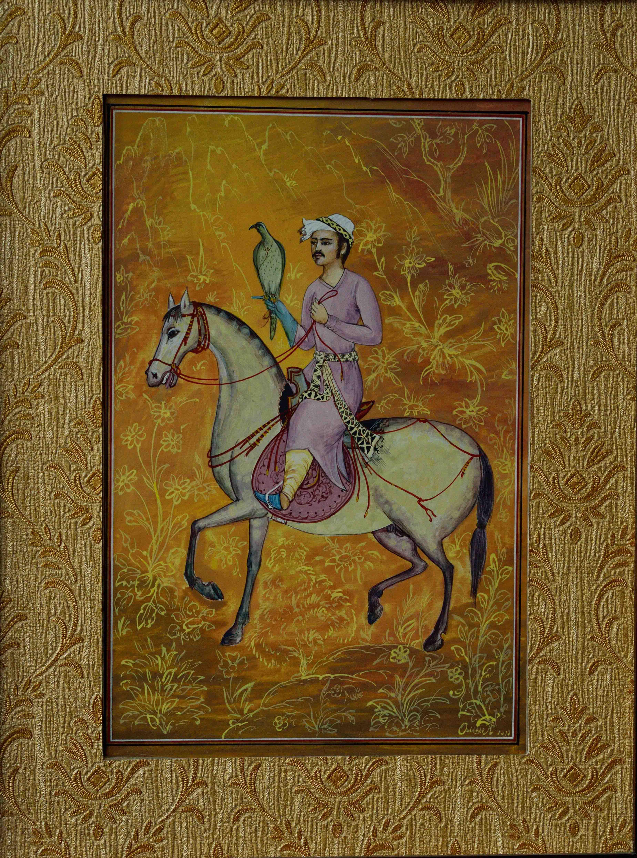 Photo of Olim Kamolzoda sitting at the desk in his workshop. He is the Honoured Artist of the Republic of Tajikistan, a Member of the Union of Artists of the Republic of Tajikistan, and a Specialist of the Miniature Art. Studying the specifics of the work